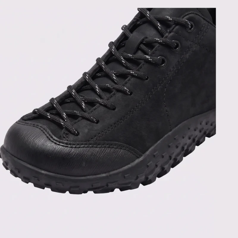 wide toe box barefoot hiking sneakers in black, close-up view of the toe on a light gray background